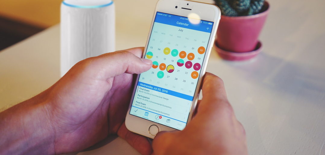 Smartphone mit Kalender und Echo (Alexa) im Hintergrund