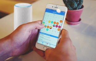Smartphone mit Kalender und Echo (Alexa) im Hintergrund