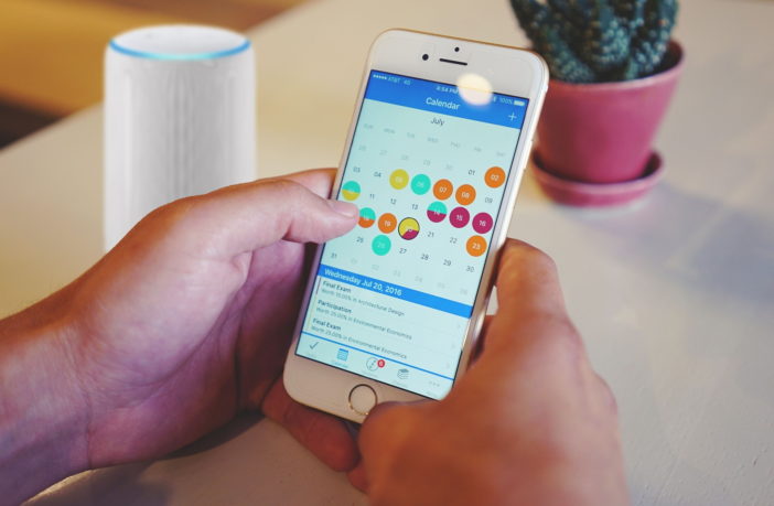 Smartphone mit Kalender und Echo (Alexa) im Hintergrund